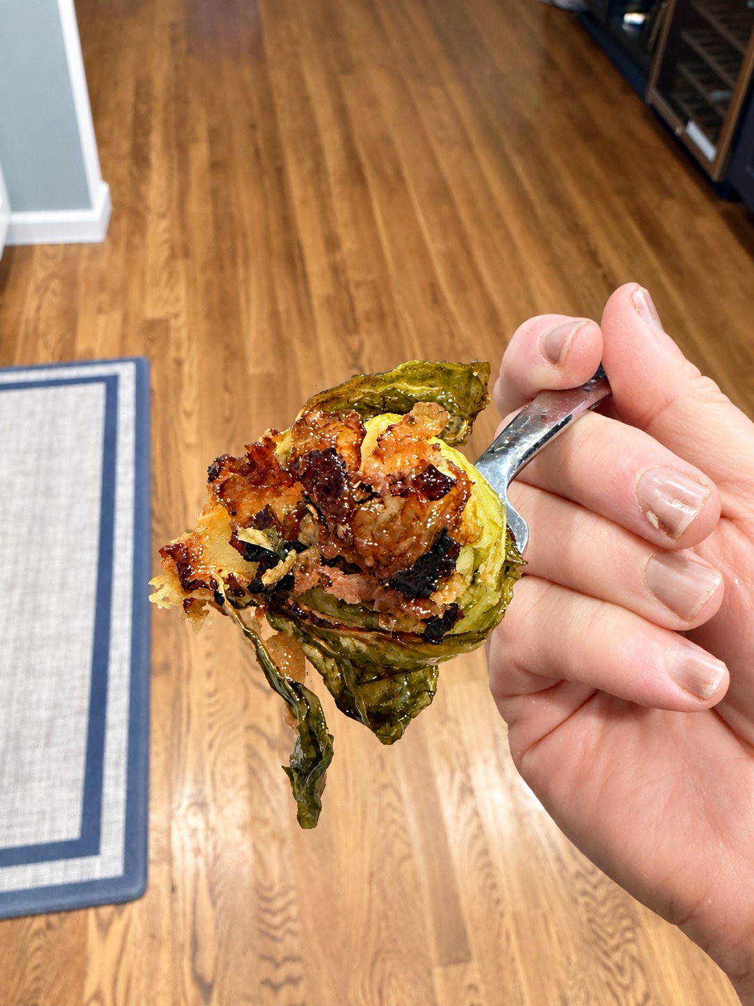 A close-up spoonful showing the deeply crisp bottom of a Parmesan Brussels sprout with bacon and onion