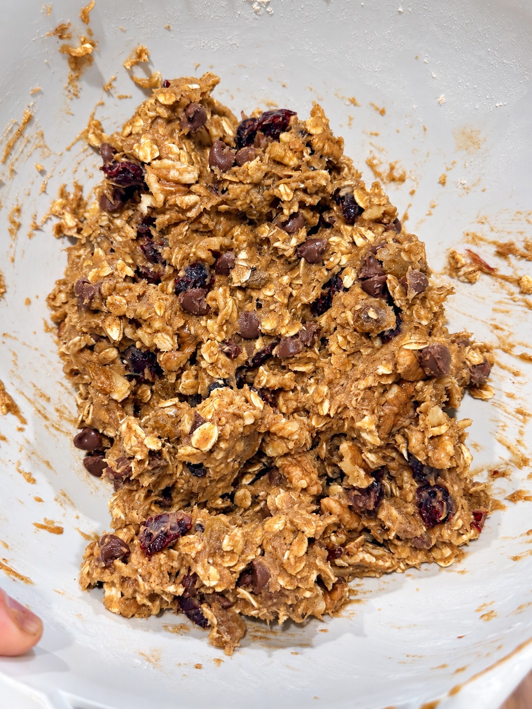 Raw banana-walnut oatmeal cookie dough loaded with chocolate chips, raisins, dried cranberries, and toasted walnuts in a mixing bowl