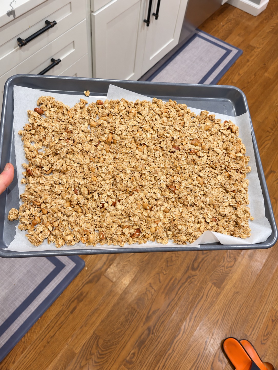 Oats and nuts pressed into an even layer on a parchment-lined baking sheet before baking